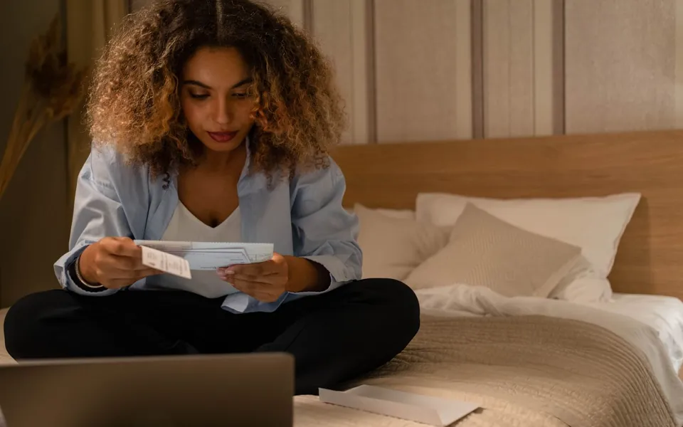 A woman sitting on her bed reading a letter from the IRS