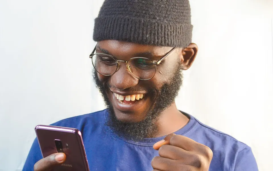 A man smiling at his phone as his tax refund status updates